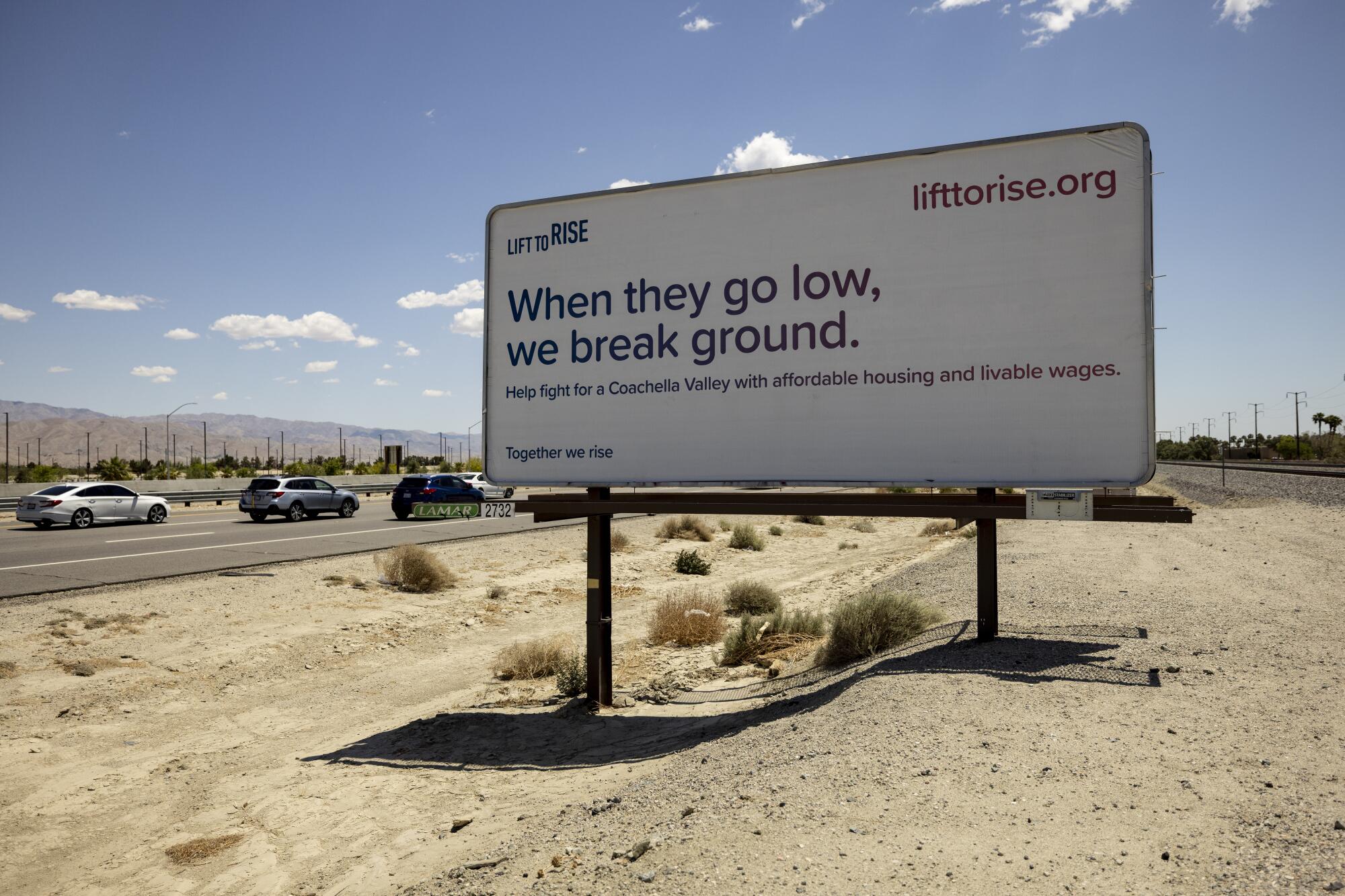 A billboard installed by Lift to Rise reads: "When they go low, we break ground."