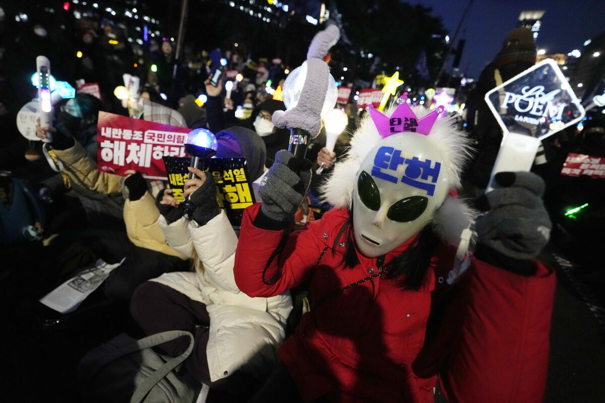 A person in a crowd wears an alien mask.