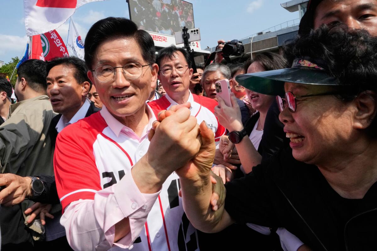 Kim Moon-soo shakes hands with a woman in a crowd.