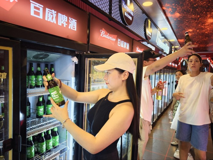 A woman looks at a bottle of beer
