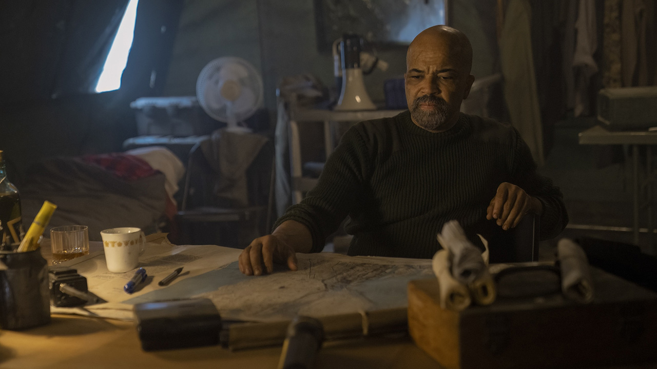 Isaac sitting at a table with a map in front of him in The Last of Us season 2 episode 7