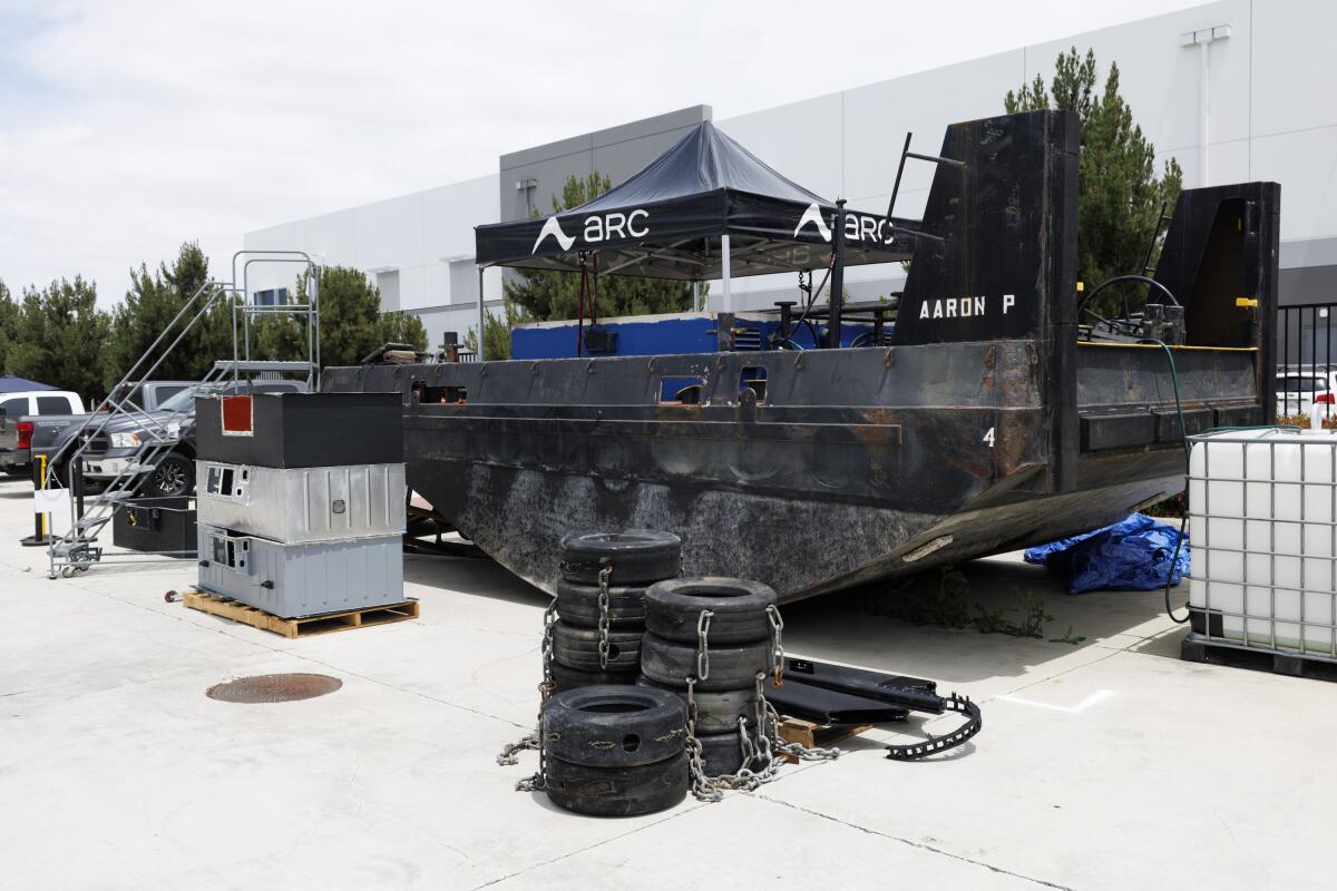 A tugboat next to tires and equipment on land.