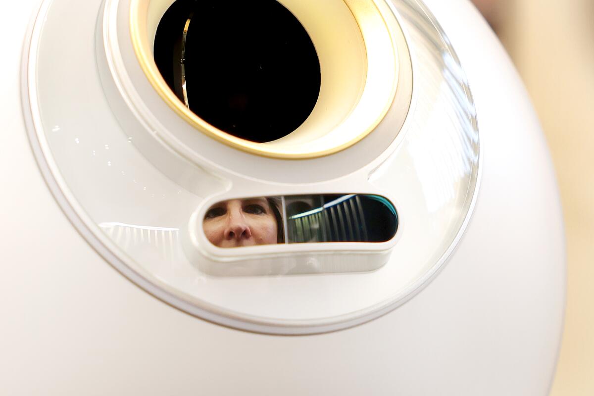 A woman is reflected in an orb while getting an eye scan.