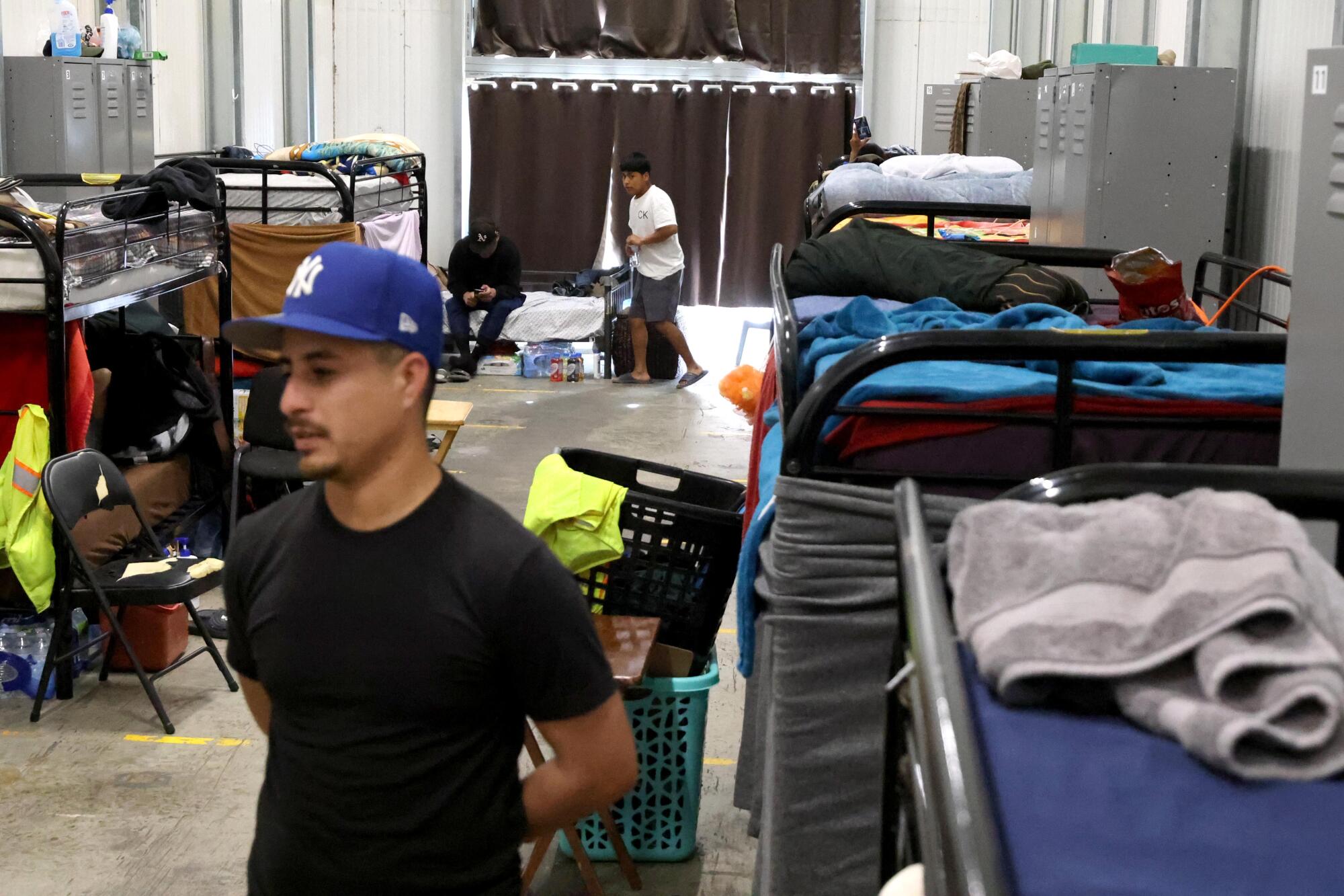 A man stands inside a dormitory room lined with bunk beds.