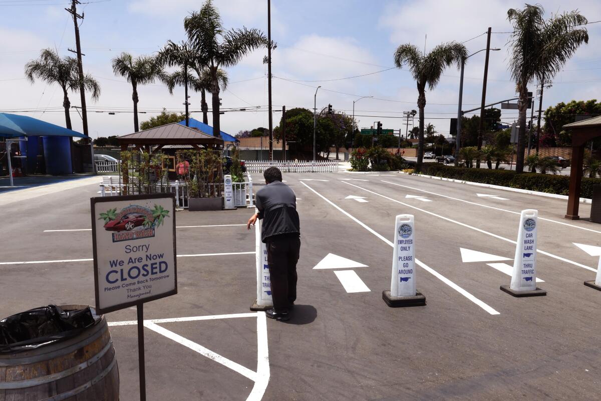 An employee of the Westchester Hand Wash stands at the car wash closed