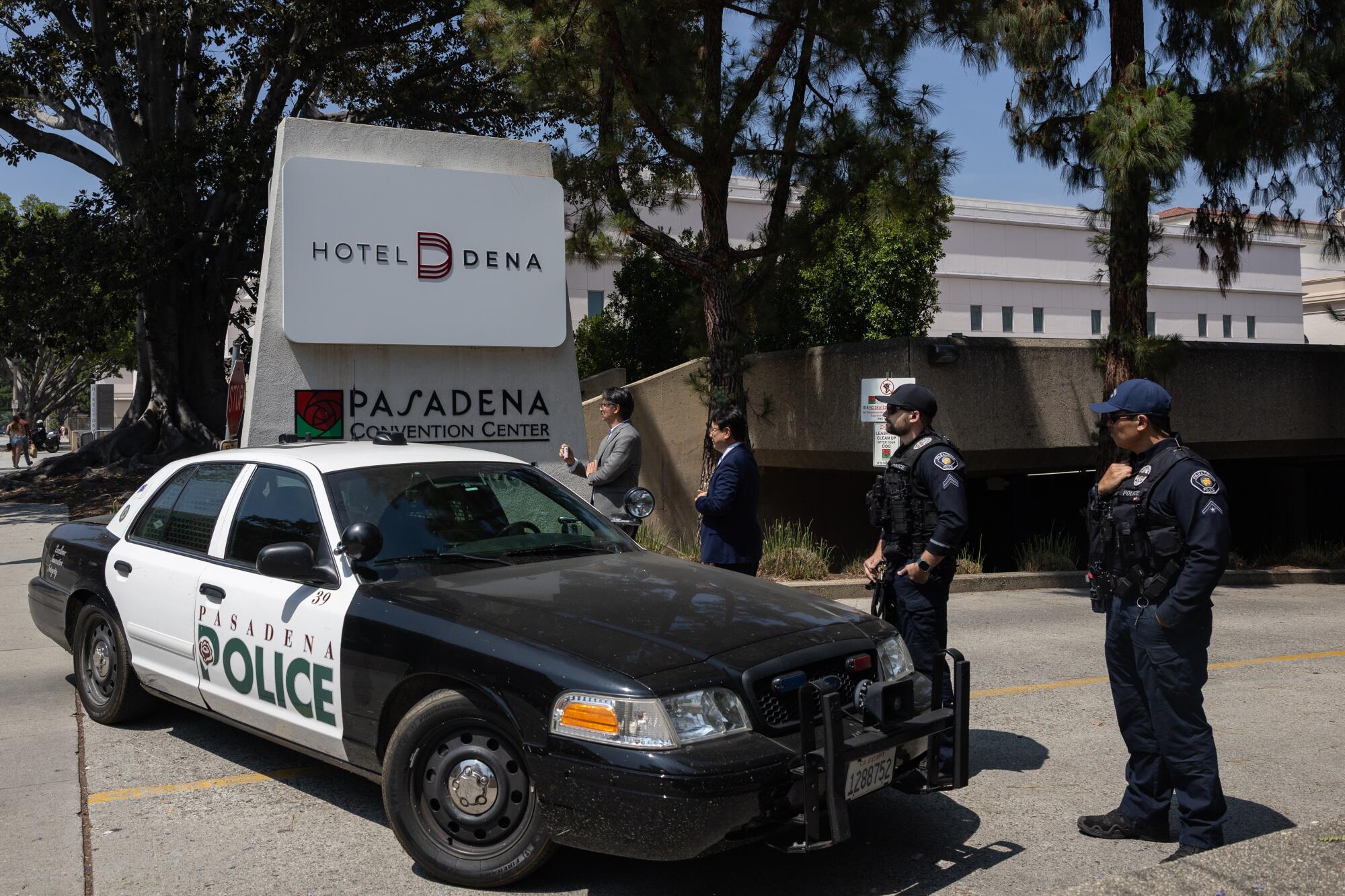 A Pasadena police cruiser and uniformed police officers block the entrance to a hotel