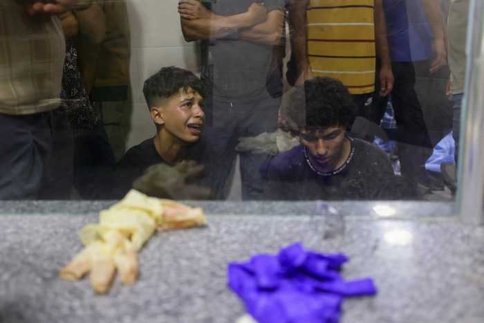 Palestinian youths mourn by the body of a relative killed in Israeli fire at a food aid distribution point set up by the privately-run Gaza Humanitarian Foundation