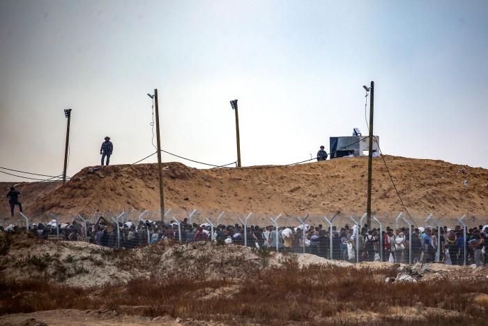 Members of a private US security company, contracted by the Gaza Humanitarian Foundation (GHF), a private US-backed aid group which the UN refuses to work with over neutrality concerns, direct displaced Palestinians as they gather to receive relief supplies at a distribution centre in the central Gaza Strip
