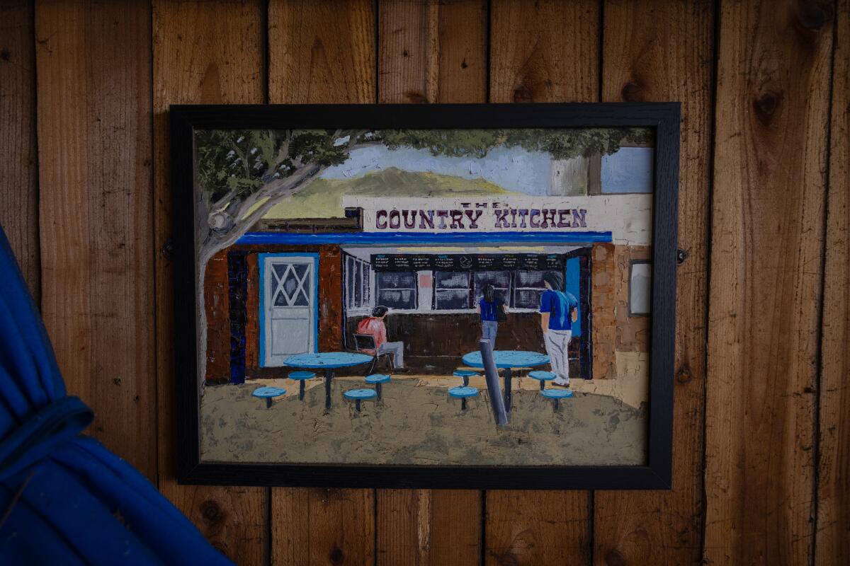 A painting of The Country Kitchen hangings on the wall of the roadside restaurant