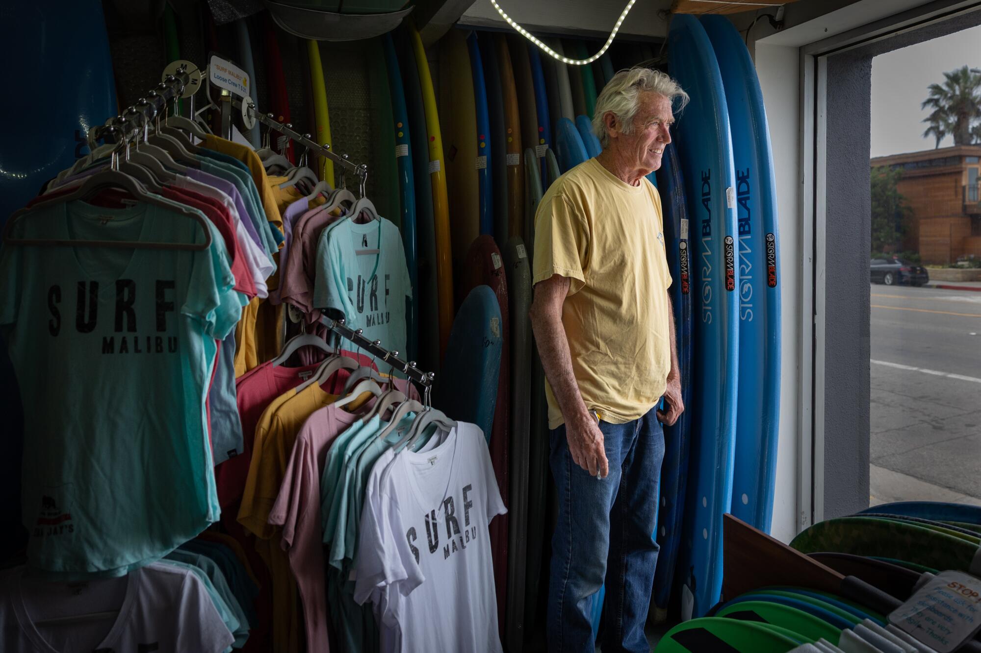 a man stands by a window in a surf shop