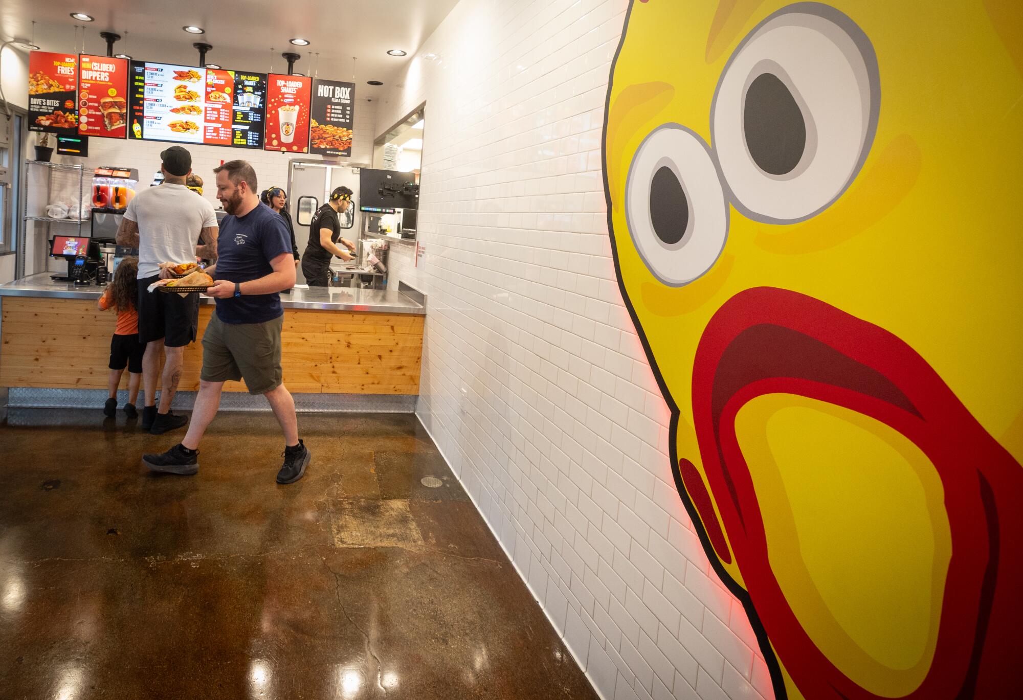 Customers order a meal beneath the signature yellow chicken at Dave's in Northridge.