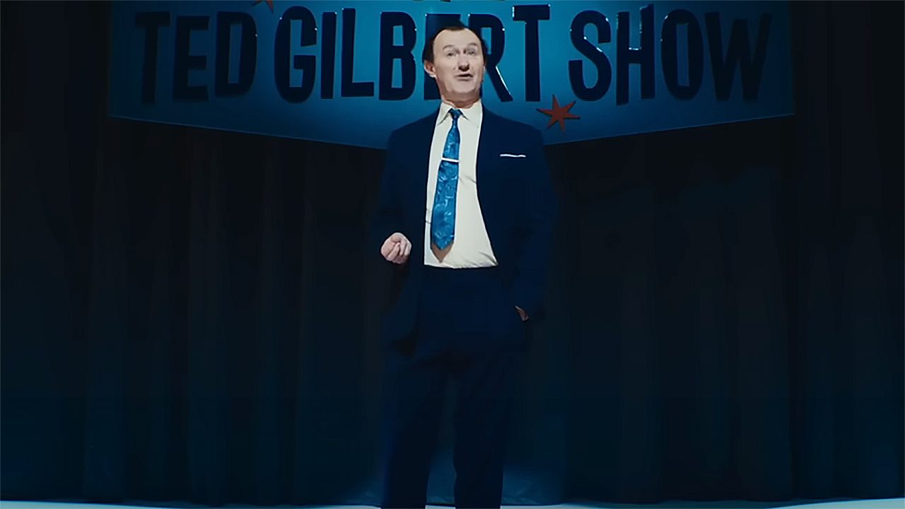 Ted Gilbert standing in front of a live, off-camera audience in The Fantastic Four: First Steps