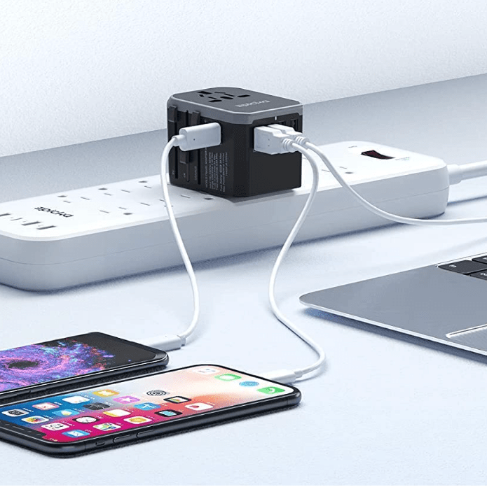Travel adaptor on power strip connected to phones and laptop.