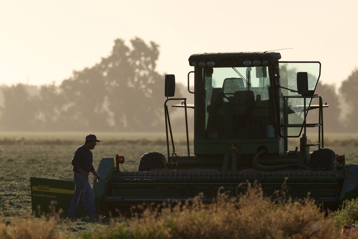 A farmworker makes repairs to a tractor in a recently harvested field Friday in Woodland.