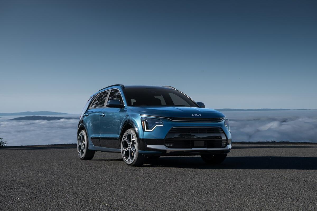 A blue vehicle on a road, with clouds in the distance