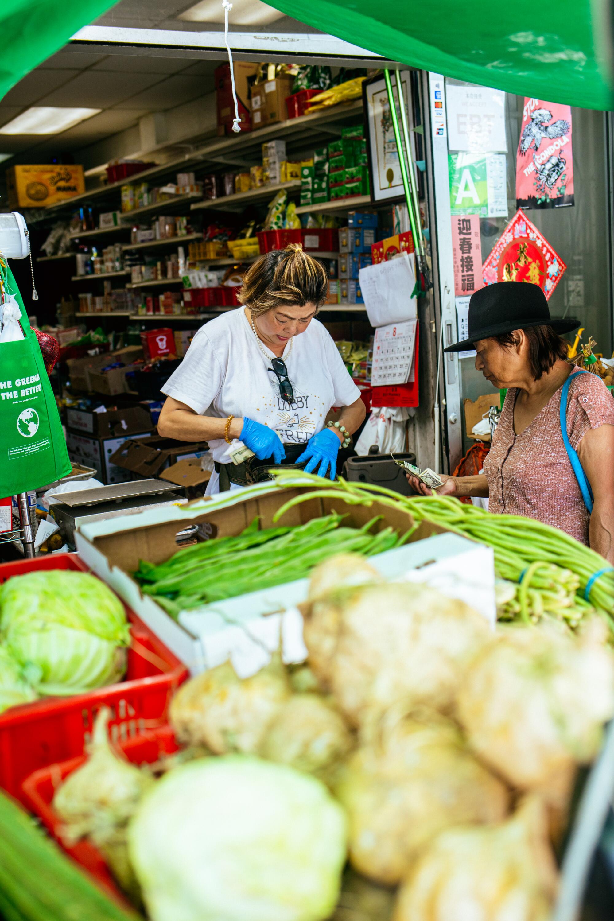 Yue Wa market owner Amy Tran discusses the price of vegetables with a customer at the store. 