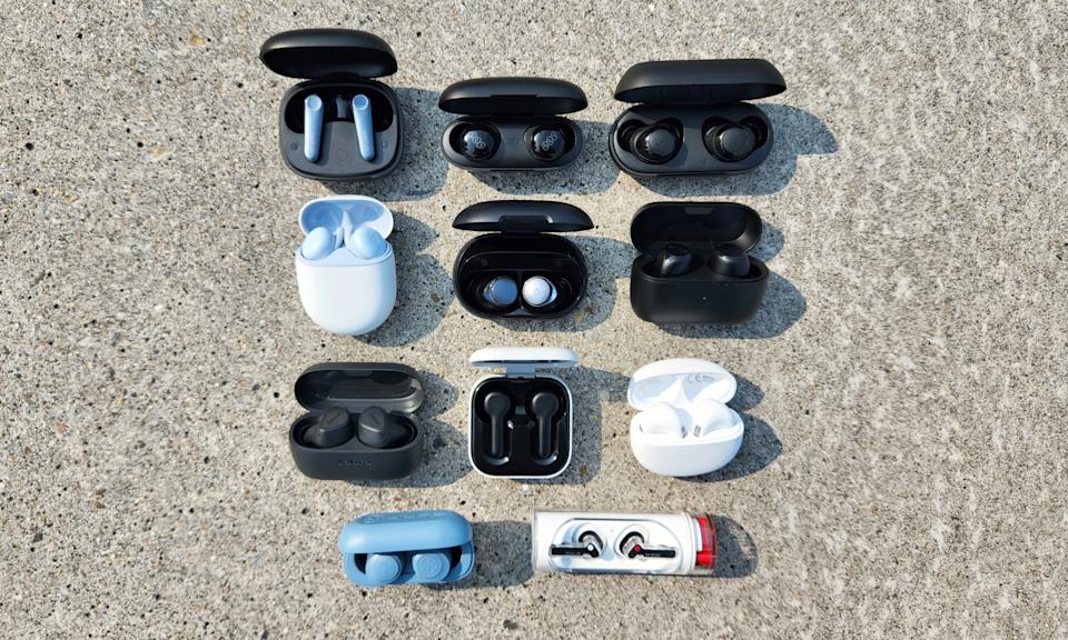 A selection of wireless earbuds sit organized in rows on a granite background.