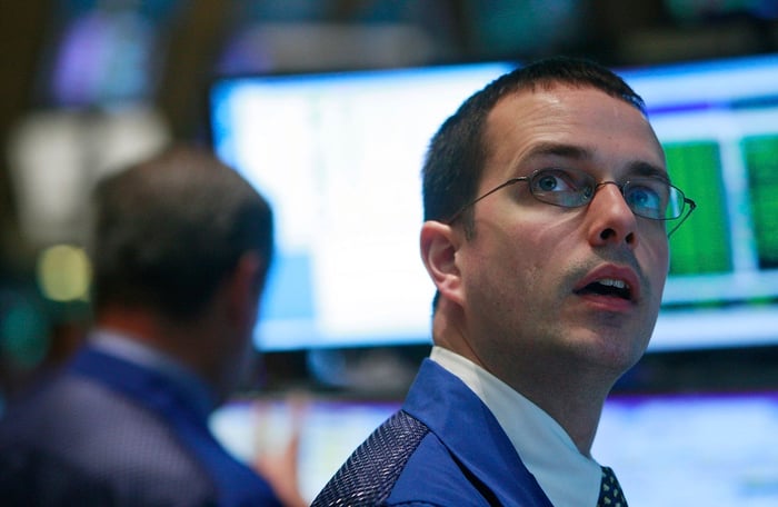 A New York Stock Exchange floor trader staring up in awe at a computer monitor.