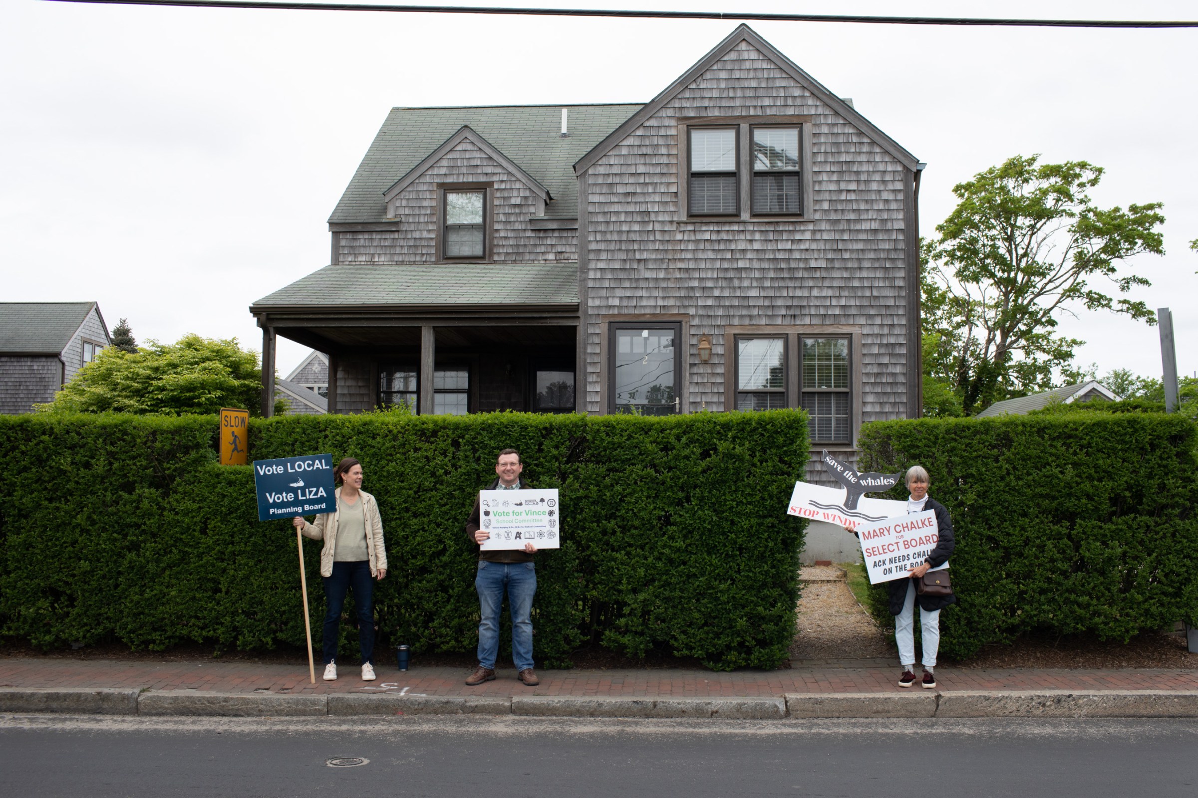 Candidates campaigned across the street from Nantucket High School, where voting was taking place for local elections in Nantucket, Massachusetts on May 20th. Running for a seat on the Select Board, Mary Chalke, right, has been strongly opposed to Vineyard Wind’s wind farm located off of Nantucket’s South Shore, claiming that it harms marine life, specifically the North Atlantic right whale.