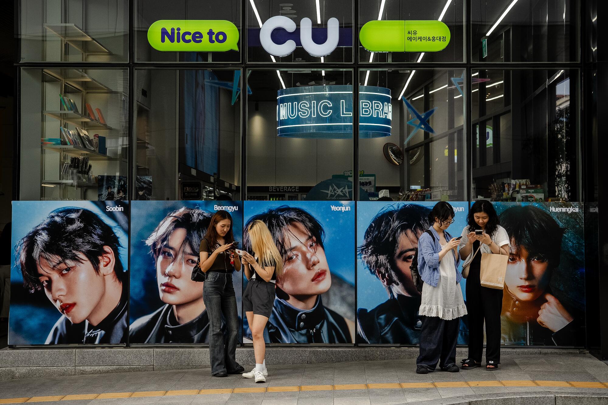 Images of a boy band decorate the windows of a convenience store.